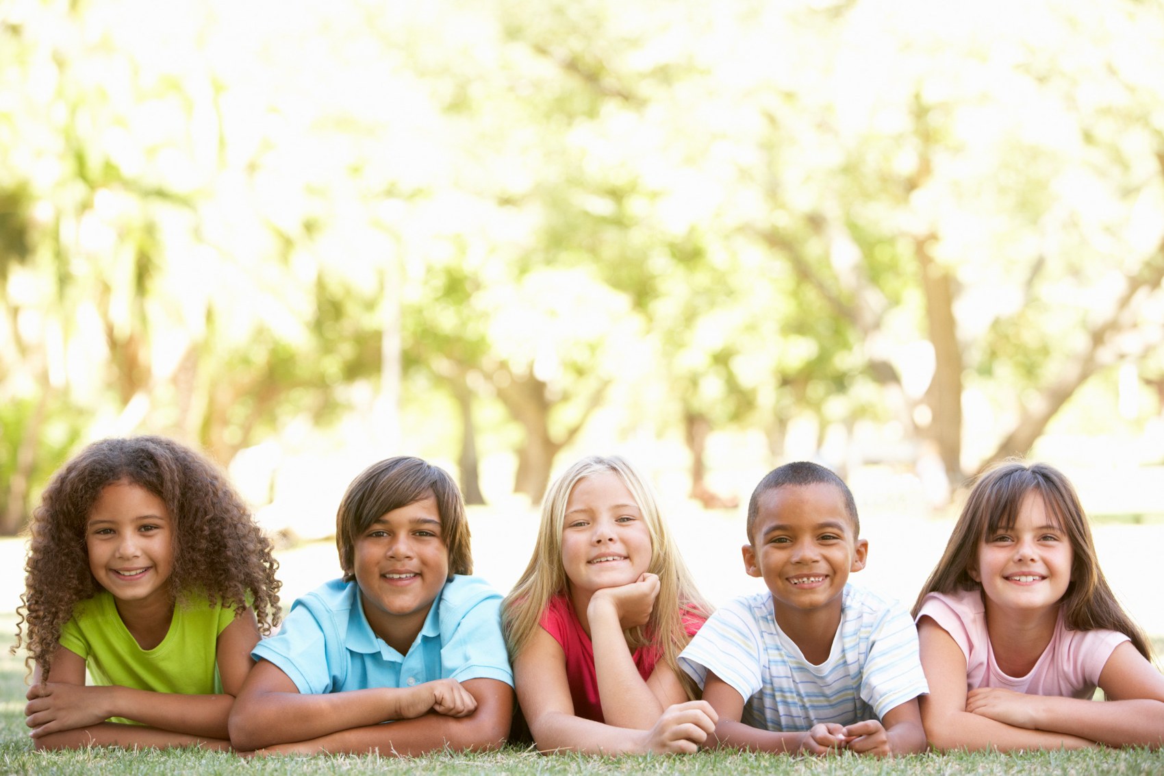 Five smiling children leaning together outdoors