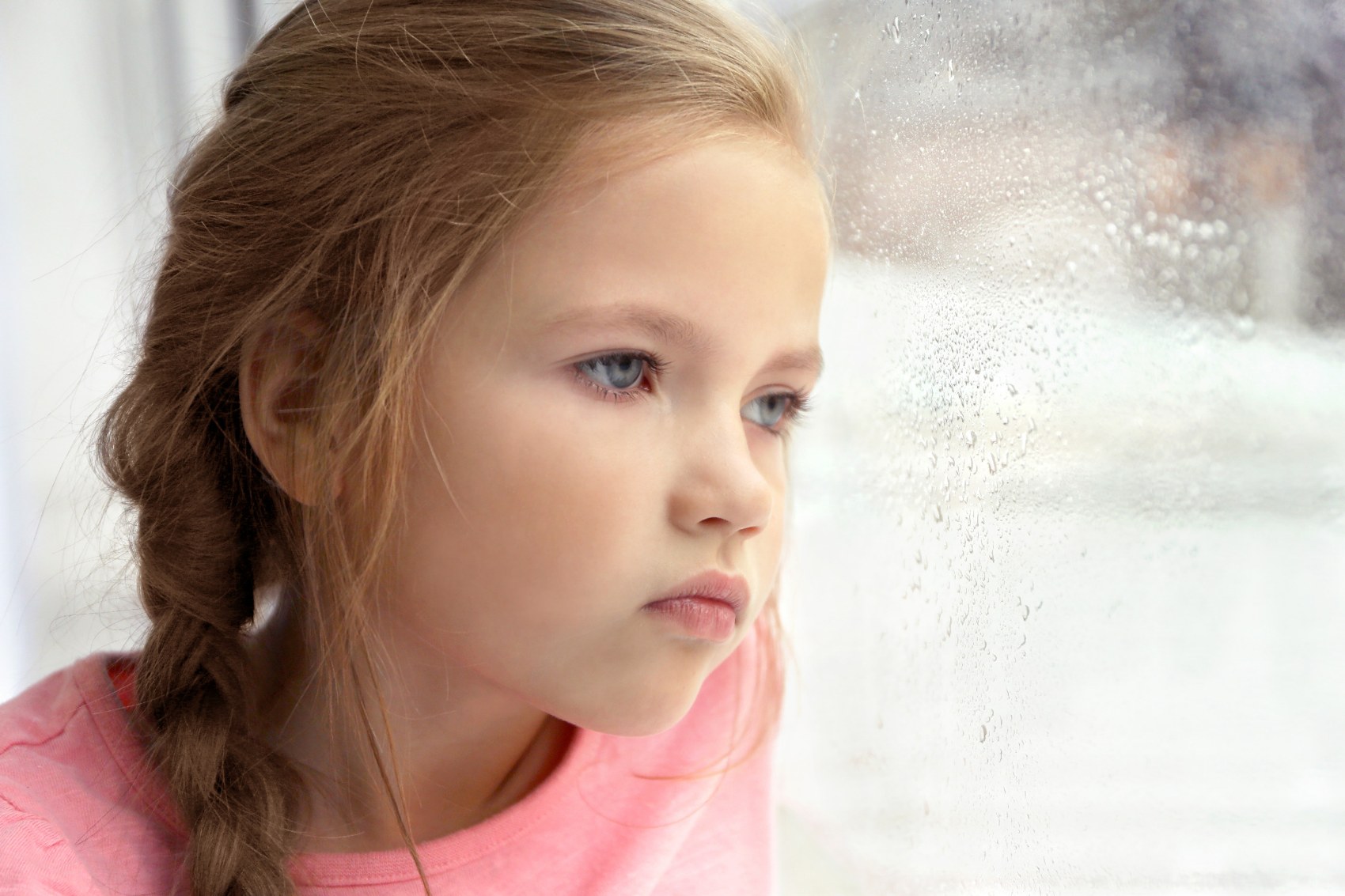 Child looking thoughtfully through a window